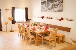 A dining area with a long wooden table set for six, surrounded by wooden chairs. - Child-friendly holiday home ALB-Traum (Hayingen)