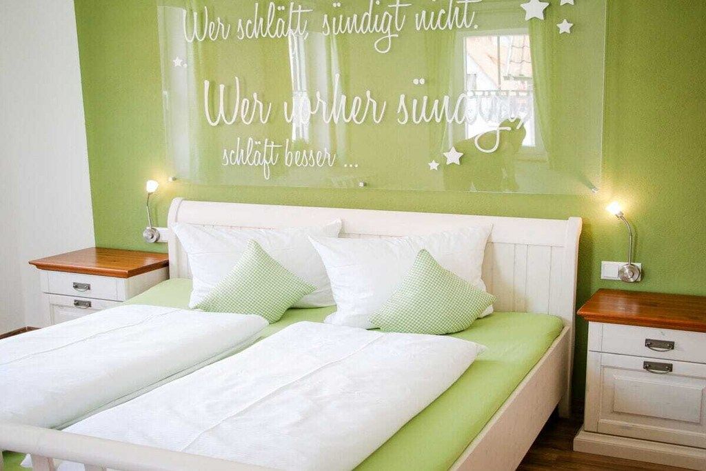 Un dormitorio con cama, mesitas de noche y una pared con una cita inspiradora.