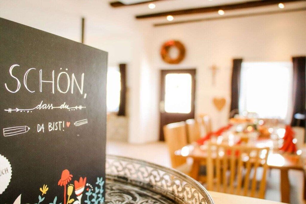 A blackboard with text and doodles, a dining area with tables and chairs, and a window with daylight.