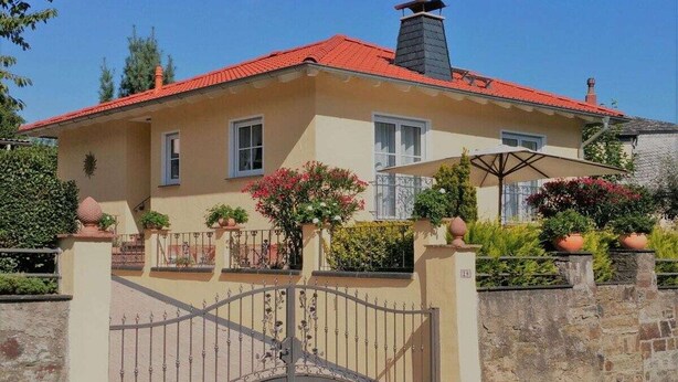 A two-story house with a red roof, a gated entrance, and potted plants. - Holiday home in Remagen with swimming pool (Remagen)