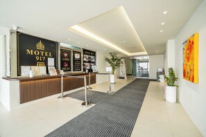 Zona de recepción de hotel con mostrador de recepción, carteles informativos y un diseño interior moderno.