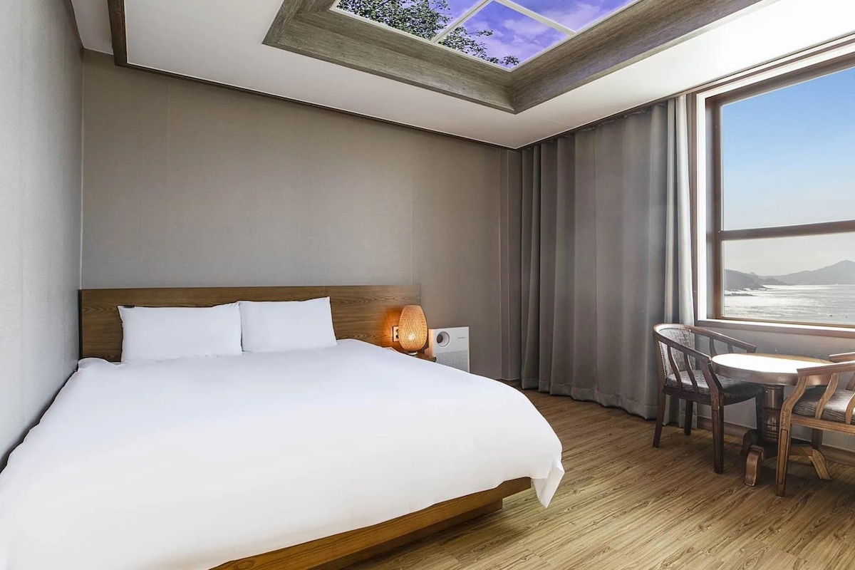 Una habitación de hotel con una cama, un escritorio y vistas al océano.