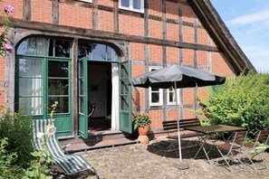 A traditional brick building with a green door, a bench, and a table with an umbrella. - "On the dike" - holiday apartment (Bremen)