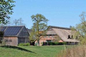 A rural property with a barn, a house with a thatched roof, and a solar panel array. - "On the dike" - holiday apartment (Bremen)