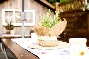 A rustic outdoor setting with a wooden table, a burlap-wrapped plant, and a white cup with a floral pattern. - Holiday home in Hayingen with swimming pool (Hayingen)