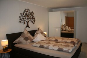 A bedroom with a bed, pillows, a nightstand, a lamp, a wall art piece, and a wardrobe. - "Abundance" - the Great (Bernkastel-Kues)
