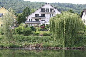 A multi-story house with a balcony, surrounded by lush greenery and a body of water. - "Abundance" - the Great (Bernkastel-Kues)