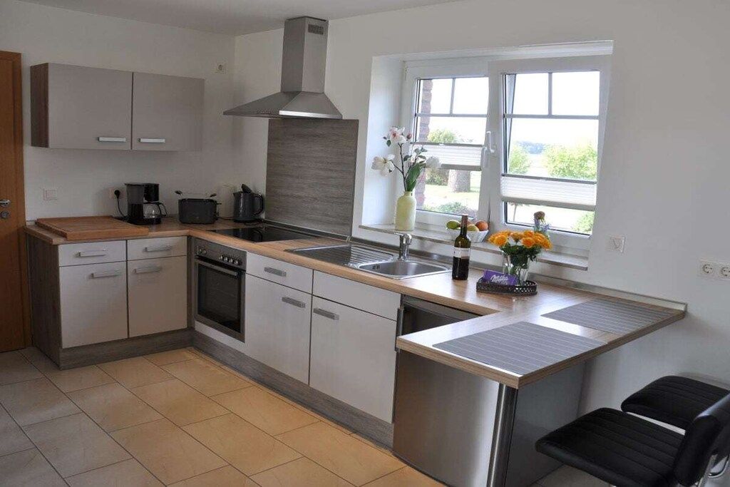 A modern kitchen with a central island, a stove, a sink, and a window with a view.