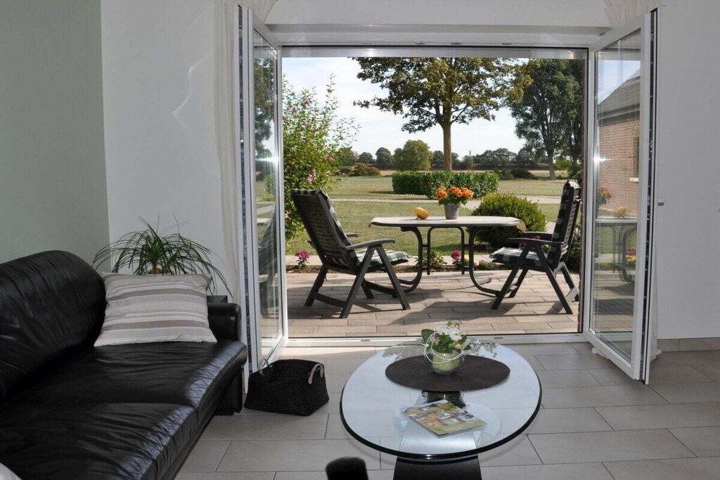 A modern living room with a glass door leading to an outdoor patio.