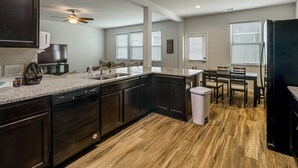 Une cuisine moderne avec des meubles de couleur bois foncé, un plan de travail en granit et un lave-vaisselle.