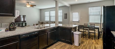 A modern kitchen with dark wood cabinets, a granite countertop, and a dishwasher.