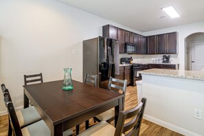 A compact kitchen with dark wooden cabinets, a stainless steel refrigerator, a microwave, and a coffee maker. - Near Highways & Hospitals! Extended Stay in Katy (Katy)