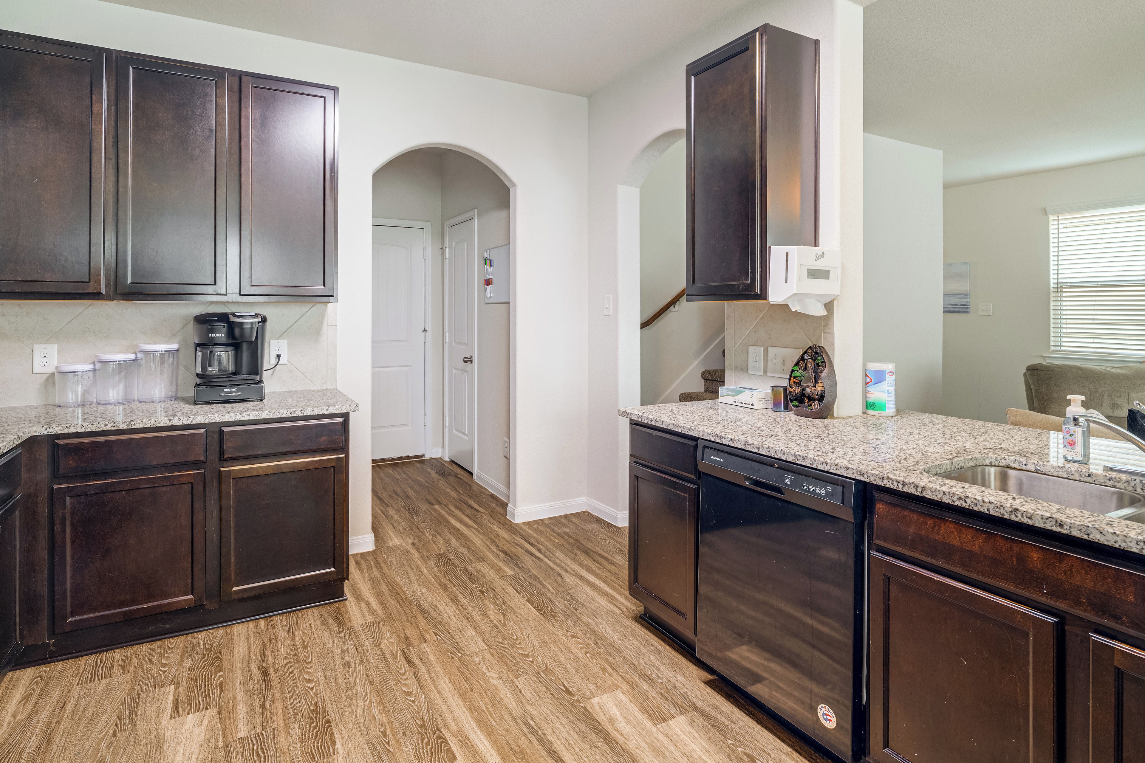 A kitchen with dark wood cabinets, a coffee maker, and a dishwasher.