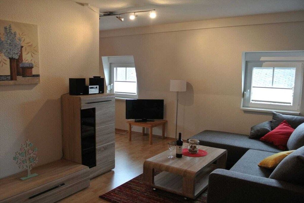 Una sala de estar con un sofá, una mesa de centro, un televisor y un mueble bajo.