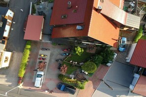 Luchtbeeld van een woongebied met meerdere huizen, een parkeerplaats en een kleine tuin.