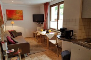 A compact living space with a sofa, dining table, and kitchenette. - Holiday apartment with 1 bedroom (Masserberg OT Fehrenbach)