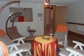 Een kamer met een ronde tafel, twee stoelen, een spiegel en een deur naar een andere kamer.