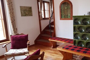Un escalier en bois avec un banc rembourré en bas, un mur recouvert de carreaux verts et une chaise en bois avec un coussin.