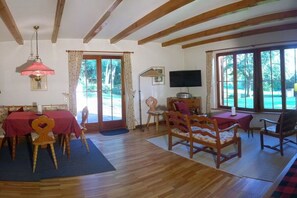 A room with a dining table, chairs, a television, and large windows. - Holiday home with 2 bedrooms (Leonberg-Warmbronn)