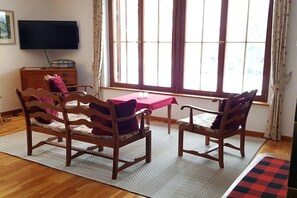 A room with a wooden table, two chairs, a television, and a window with curtains. - Holiday home with 2 bedrooms (Leonberg-Warmbronn)