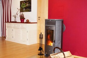 A room with a white cabinet, a red wall, and a wood-burning stove. - Panoramic view of the Höllbach valley (Rettenbach)