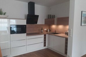 Een moderne keuken met witte kastjes, een zwarte afzuigkap en een houten aanrecht.