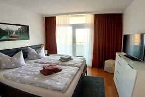A hotel room with a bed, a television, a painting, and a view of the outdoors. - Kristin Pohl holiday apartment (Bad Harzburg)