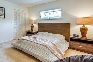 A bedroom with a bed, bedside tables, a nightstand, a window, and a door with louvered shutters. - Bring Your Boat! Waterfront Clearwater Gem w/ Pool (Clearwater)