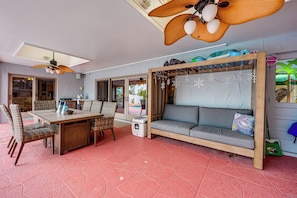 Una habitación con una mesa de comedor, sillas de mimbre, un sofá y un ventilador de techo.