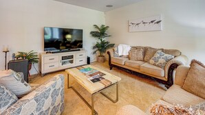 A living room with a television, sofa, coffee table, and decorative items. - Bring Your Boat! Waterfront Clearwater Gem w/ Pool (Clearwater)