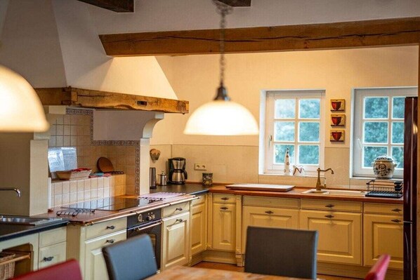 A kitchen with a wooden ceiling, a window with a view, and a hanging light fixture.