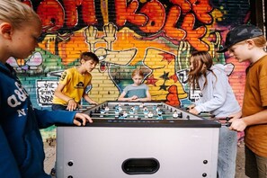 A group of people playing foosball in front of a graffiti-covered wall.