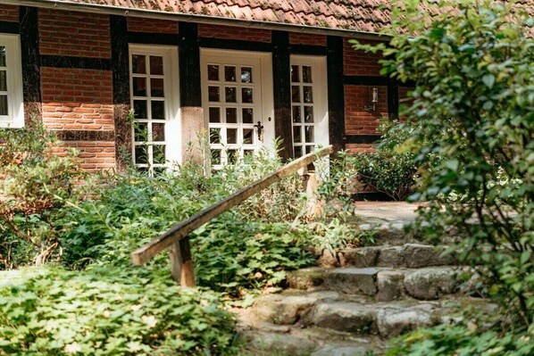 A traditional brick house with a wooden staircase leading to a white door.