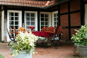 A patio with a table and chairs, surrounded by potted plants and a brick wall.