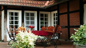 A patio with a table and chairs, surrounded by potted plants and a brick wall.