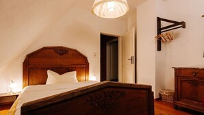 A bedroom with a wooden bed, a nightstand, a lamp, and a wooden dresser.