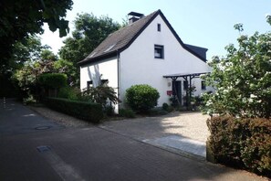 A white building with a gabled roof, a covered porch, and a gravel driveway. - Gingerbread House Xanten (Xanten)