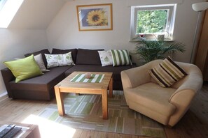 Ein Wohnzimmer mit einer Couch, einem Sessel, einem Couchtisch und einer Pflanze.