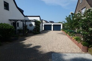 Ein Einfahrt zum Wohnhaus, die zu einer Garage mit Kiesbelag und einem Pflasterweg führt.