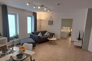 A modern living room with a sofa, a dining table set for two, and a small side table.