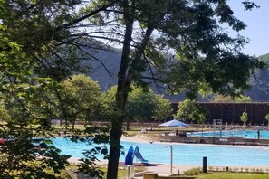 A swimming pool with a slide, surrounded by trees and a mountain backdrop. - Holiday apartment with 1 bedroom (Bad Kreuznach)