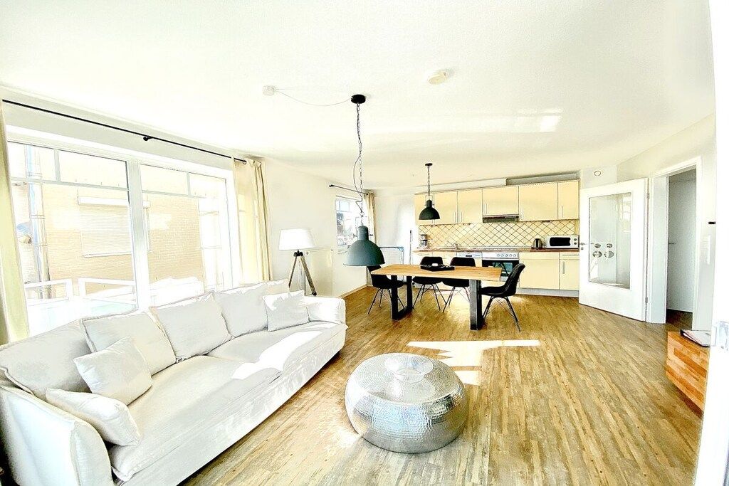 A modern living room with a sofa, a round coffee table, and a dining area with a table and chairs.
