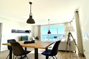 A dining area with a wooden table, four chairs, and two pendant lights. - Beach oasis beach shell (Sierksdorf)