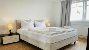 Una habitación de hotel con cama, mesitas de noche y una ventana con cortinas.