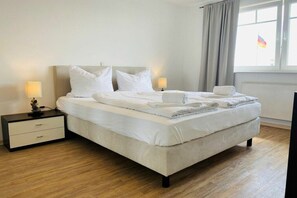 A hotel room with a bed, bedside tables, and a window with curtains. - Beach oasis beach shell (Sierksdorf)