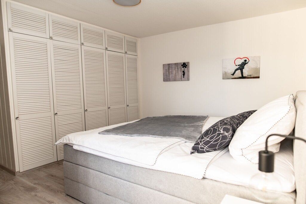 Une chambre à coucher avec un lit, une table de chevet, une lampe et une armoire.
