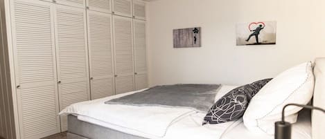 Un dormitorio con una cama, una mesita de noche, una lámpara y un armario.