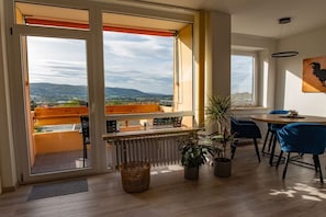 A room with a balcony, a dining area, and a view of the countryside. - Holiday apartment with 1 bedroom (Bad Harzburg)