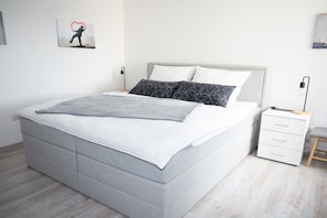 A modern bedroom with a bed, bedside tables, and a nightstand. - Holiday apartment with 1 bedroom (Bad Harzburg)