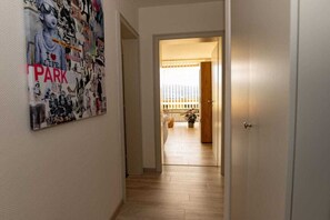 Un pasillo con un cartel en la pared, una puerta que da a un balcón y suelo de madera.